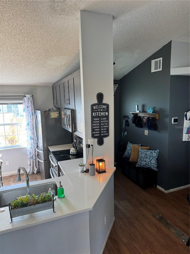 kitchen featuring visible vents, stainless steel appliances, light countertops, and dark wood-style flooring