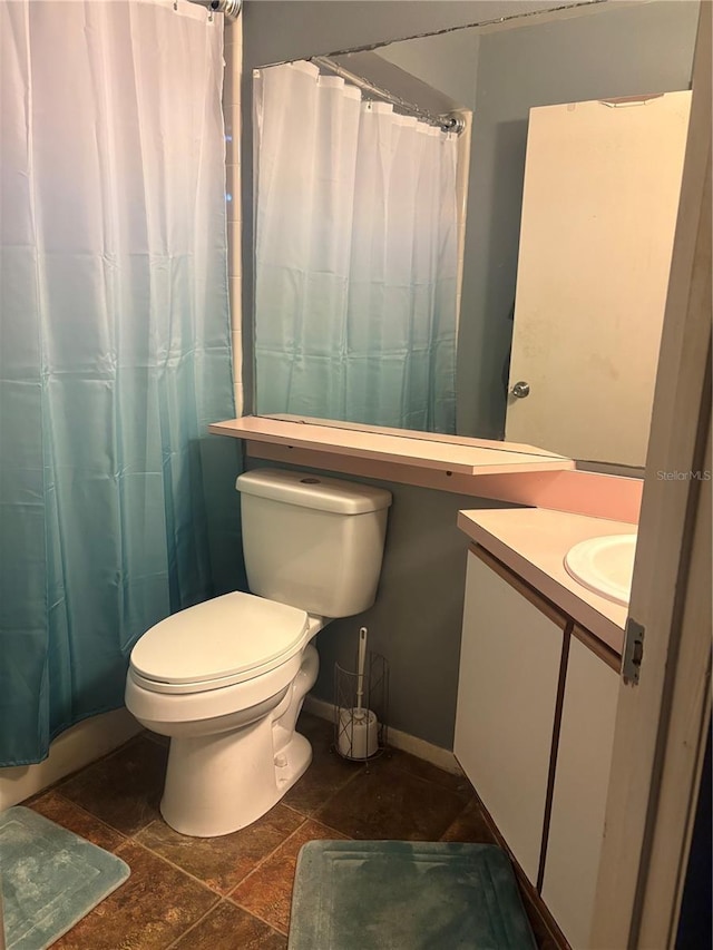 full bath with curtained shower, stone finish floor, toilet, and vanity