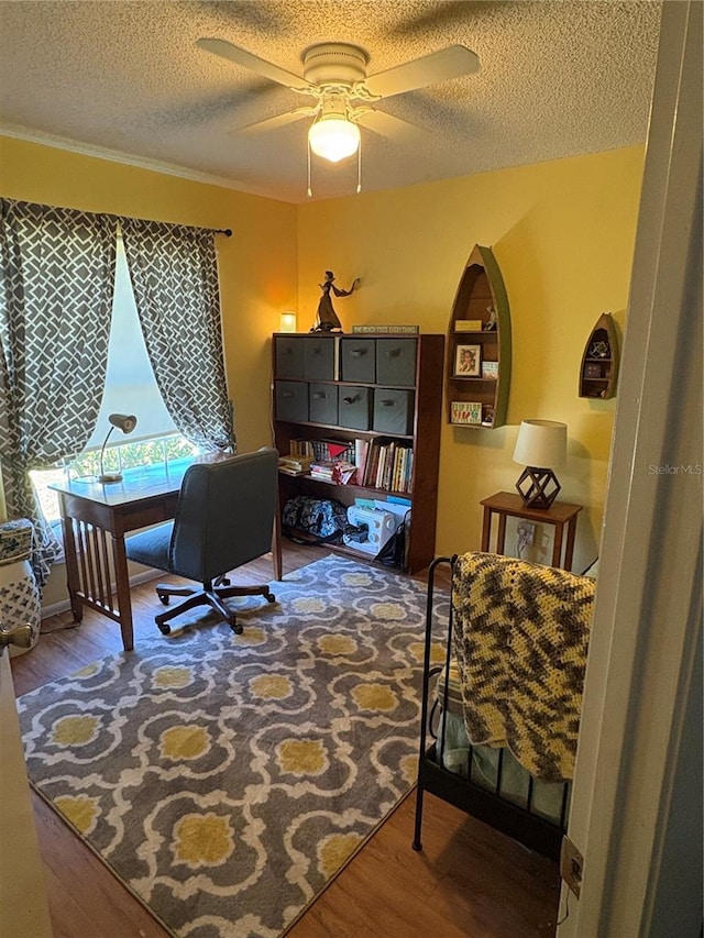 home office featuring ceiling fan, arched walkways, a textured ceiling, and wood finished floors