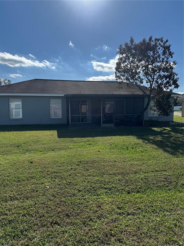 rear view of property featuring a lawn and a sunroom