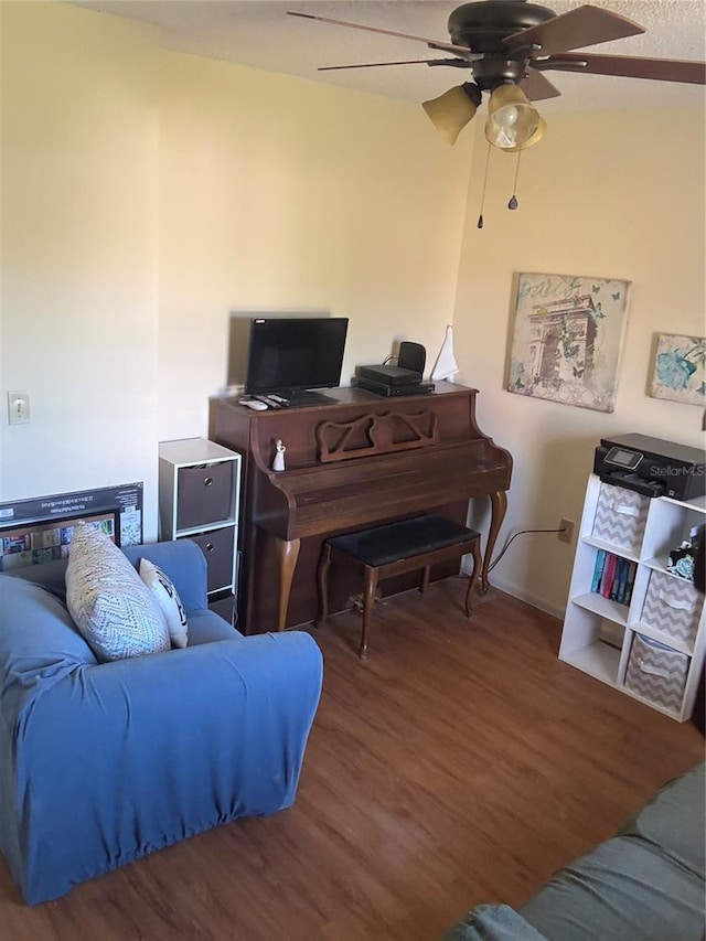 living area with wood finished floors, baseboards, and ceiling fan