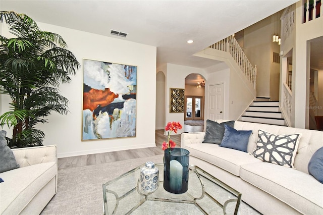 living area featuring visible vents, stairway, arched walkways, and wood finished floors