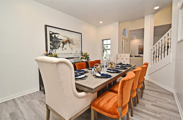 dining space with a textured ceiling, light wood-style flooring, recessed lighting, baseboards, and stairs