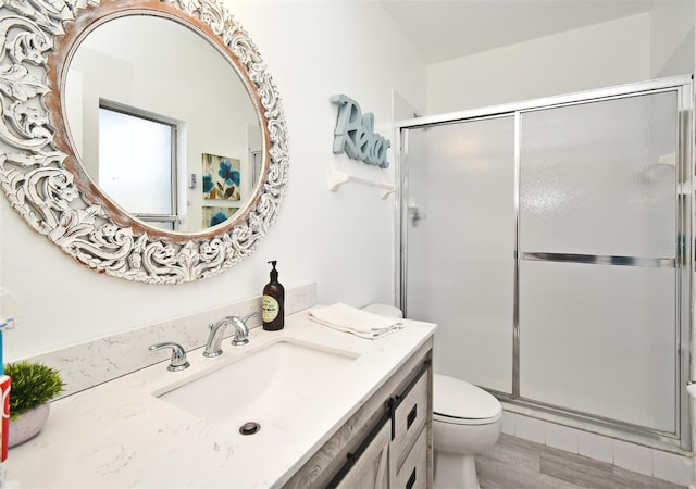 full bath with toilet, a shower with door, wood finished floors, and vanity