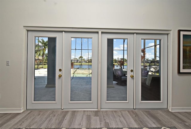 doorway featuring french doors, a water view, and wood finished floors