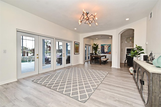 entryway with arched walkways, recessed lighting, a notable chandelier, visible vents, and light wood-style floors