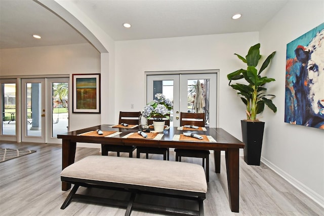 dining room featuring a healthy amount of sunlight, light wood-style flooring, and french doors