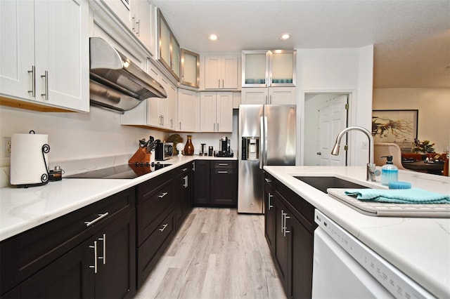 kitchen featuring glass insert cabinets, white cabinetry, a sink, stainless steel fridge, and dishwasher