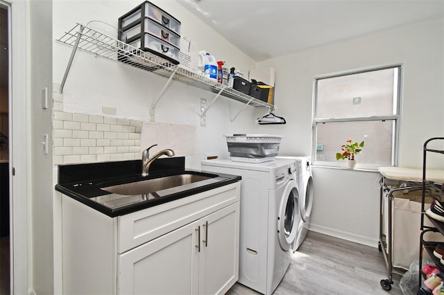 laundry area featuring light wood-style flooring, a sink, baseboards, cabinet space, and washing machine and clothes dryer