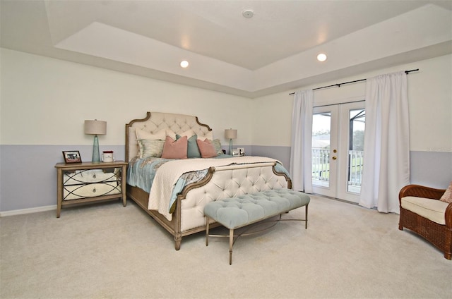 bedroom with light colored carpet, access to outside, a tray ceiling, french doors, and recessed lighting