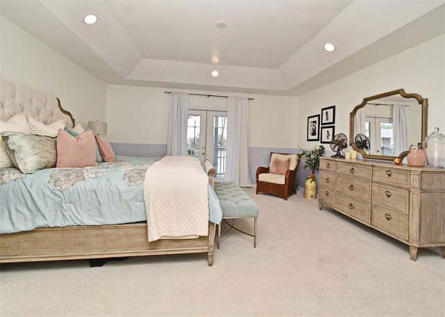 bedroom with light carpet, recessed lighting, a tray ceiling, and french doors