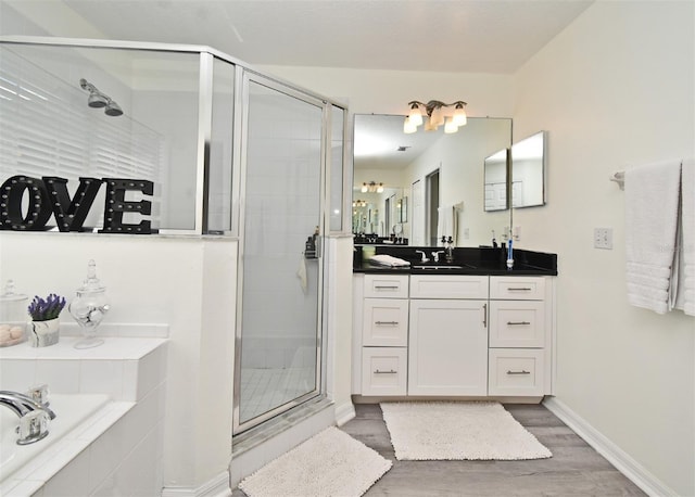 full bath featuring a stall shower, wood finished floors, vanity, and baseboards