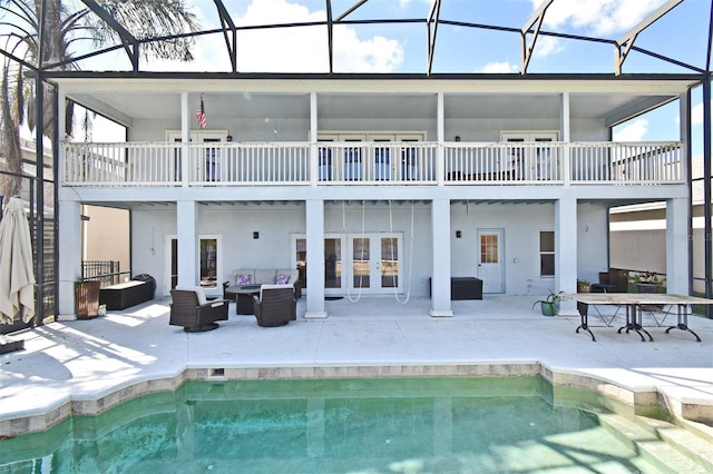 rear view of house with a patio area, glass enclosure, an outdoor pool, and an outdoor hangout area