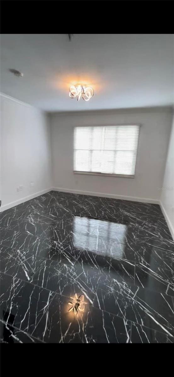 empty room featuring marble finish floor and baseboards