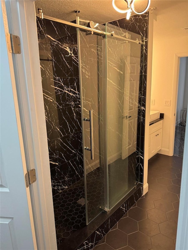 full bathroom with a textured ceiling, a marble finish shower, vanity, and tile patterned floors