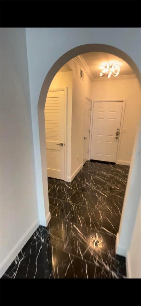 hall with arched walkways, marble finish floor, baseboards, and crown molding