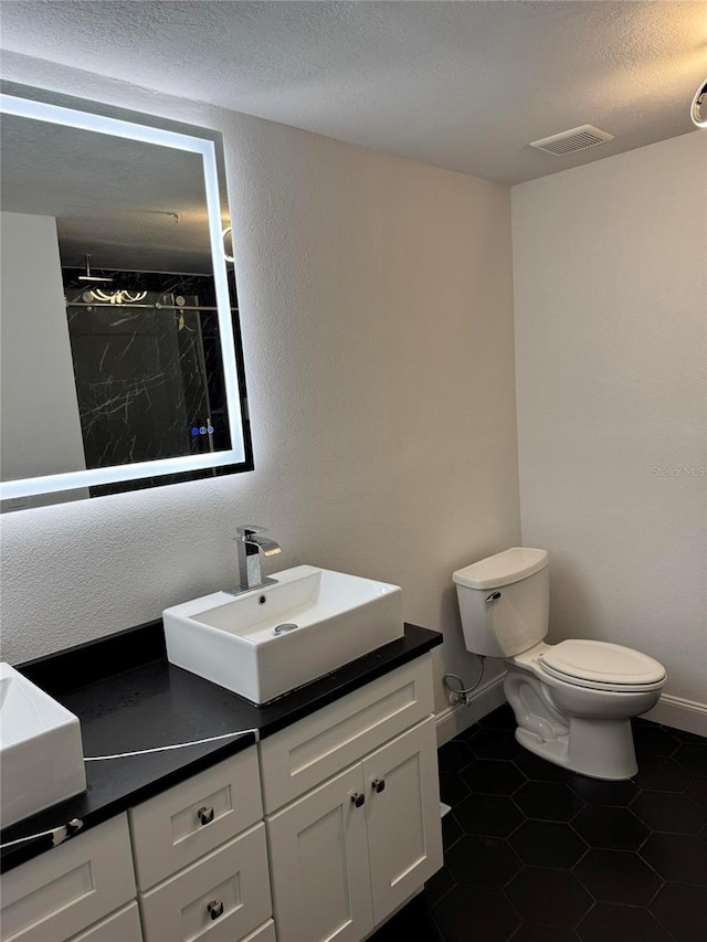 full bath featuring a shower, visible vents, toilet, vanity, and a textured ceiling