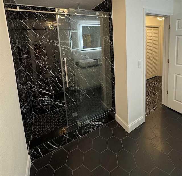 full bath with tile patterned floors, a marble finish shower, and baseboards