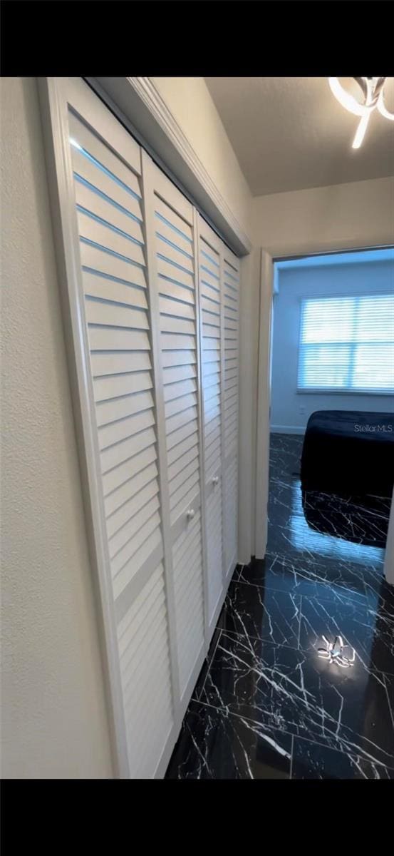 corridor with a textured wall and marble finish floor