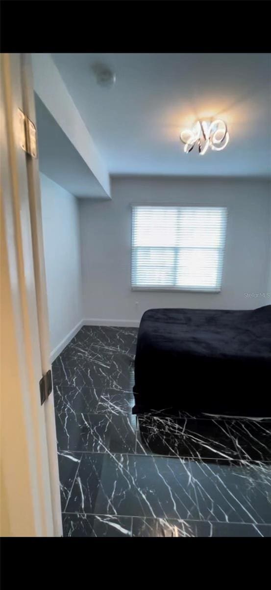 bedroom with marble finish floor and baseboards