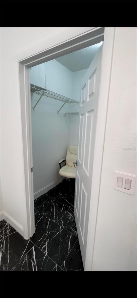 bathroom with marble finish floor, toilet, and baseboards