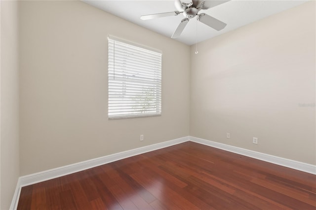 spare room featuring a ceiling fan, dark wood finished floors, and baseboards