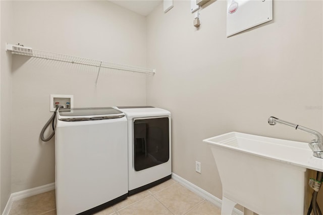 washroom featuring light tile patterned floors, a sink, laundry area, independent washer and dryer, and baseboards