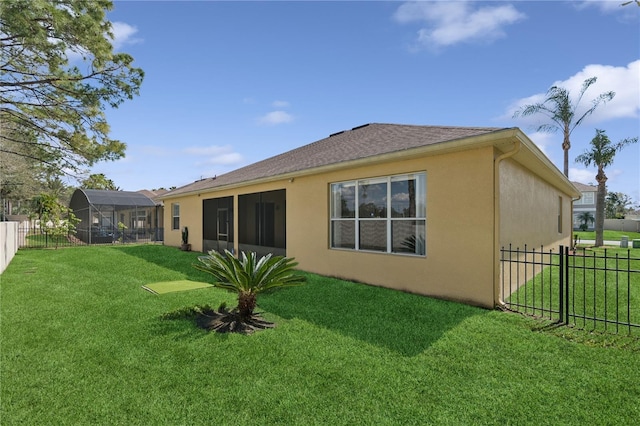 back of house featuring a lanai, a lawn, fence private yard, and stucco siding