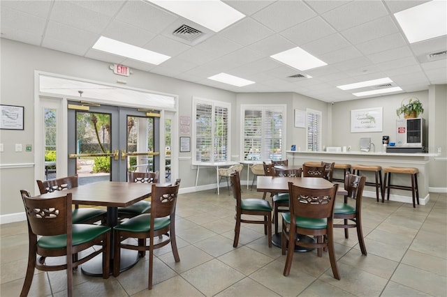 dining area with a paneled ceiling, french doors, visible vents, and baseboards