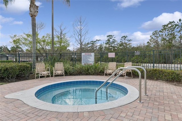 view of pool featuring fence and a hot tub