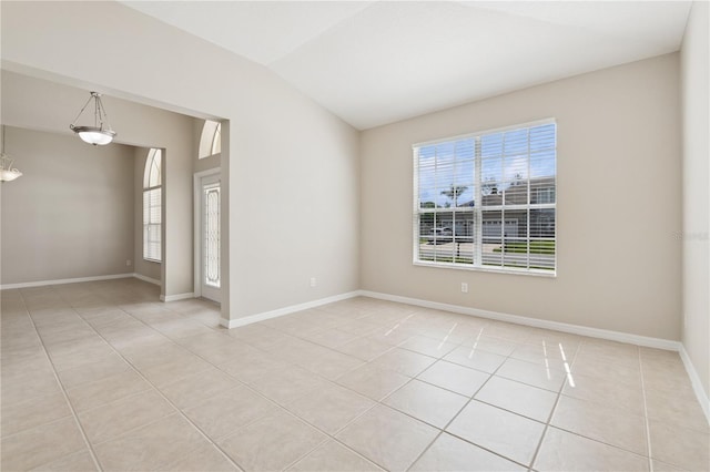 spare room with light tile patterned floors, lofted ceiling, and baseboards