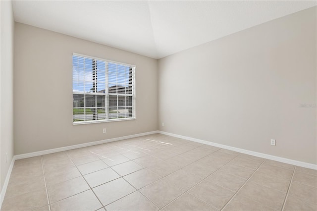 spare room featuring light tile patterned flooring and baseboards