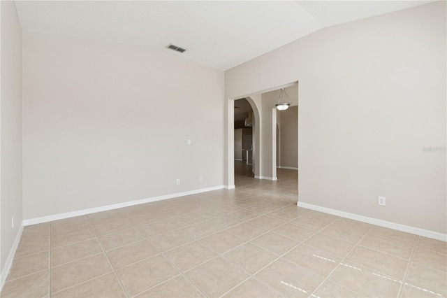 unfurnished room featuring arched walkways, visible vents, vaulted ceiling, and baseboards