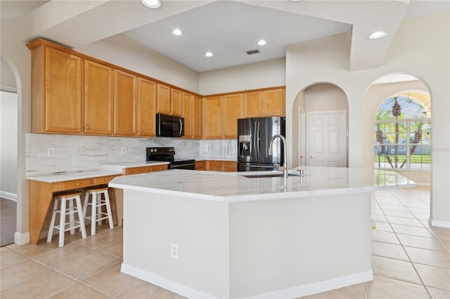 kitchen with light tile patterned floors, tasteful backsplash, visible vents, black appliances, and a sink