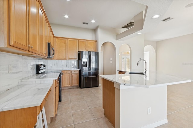 kitchen with visible vents, a sink, black appliances, backsplash, and light tile patterned flooring