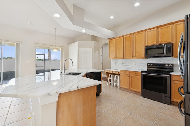 kitchen featuring decorative backsplash, stainless steel appliances, a large island with sink, a sink, and light tile patterned flooring