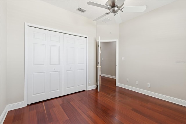 unfurnished bedroom with dark wood-type flooring, a closet, visible vents, and baseboards