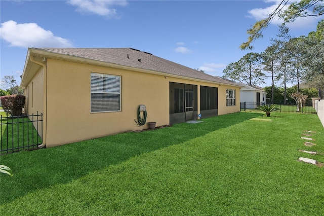 back of house featuring a yard, fence private yard, a sunroom, and stucco siding