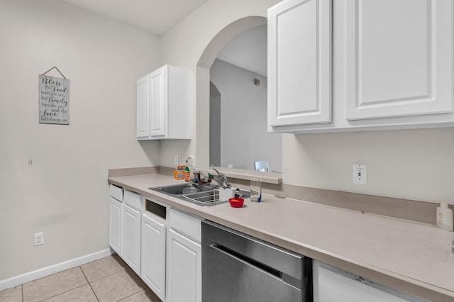 kitchen featuring light tile patterned floors, light countertops, stainless steel dishwasher, white cabinets, and a sink