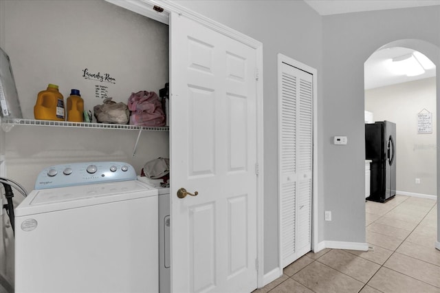 washroom with laundry area, baseboards, arched walkways, washer / clothes dryer, and light tile patterned flooring