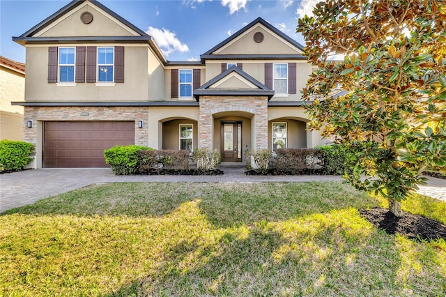 view of front of property with decorative driveway, a front yard, stone siding, and stucco siding