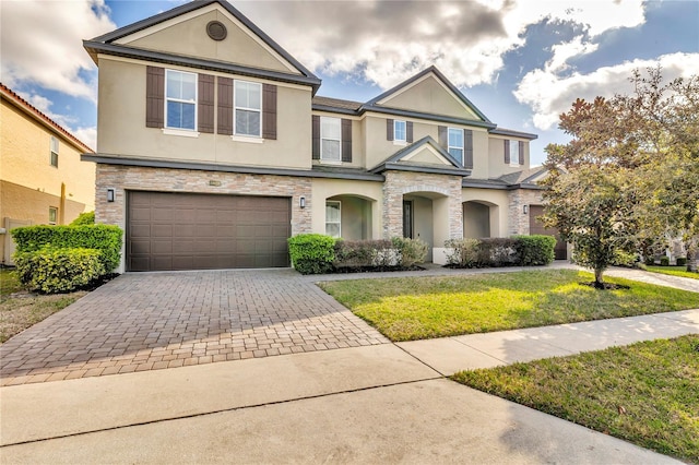 view of front of property featuring stone siding, decorative driveway, and stucco siding