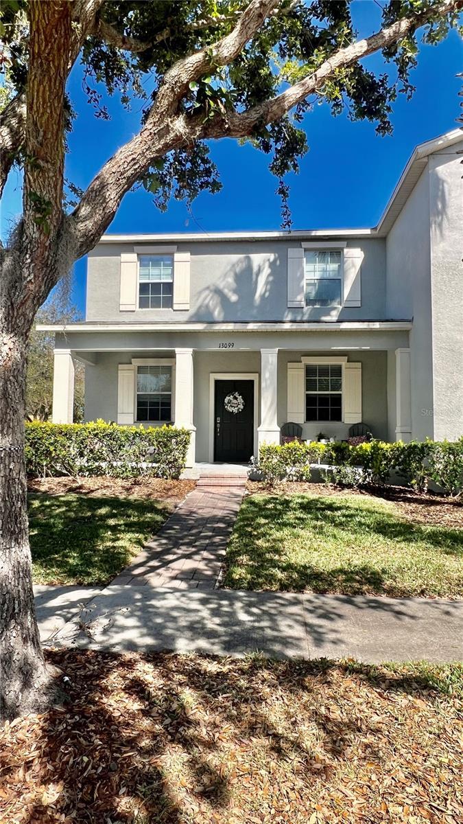 view of front of house featuring covered porch, a front lawn, and stucco siding