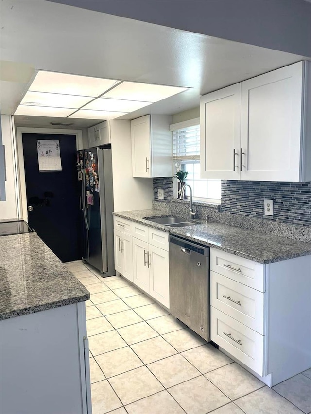 kitchen with dishwasher, a sink, freestanding refrigerator, and white cabinets