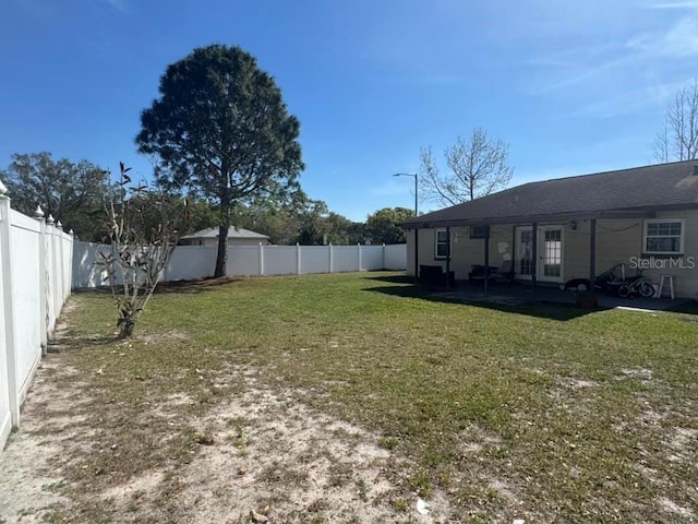 view of yard with a patio area, french doors, and a fenced backyard