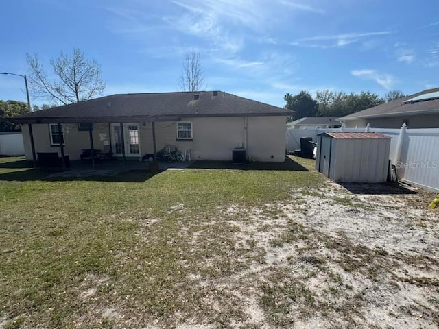 rear view of house featuring a patio, a fenced backyard, an outbuilding, a yard, and a shed