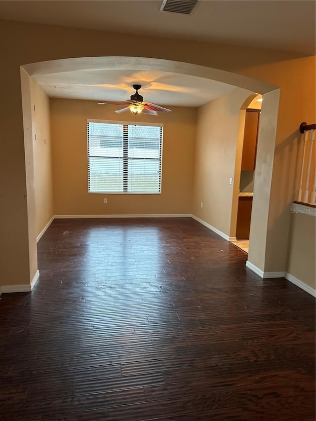 unfurnished room featuring arched walkways, ceiling fan, and dark wood finished floors