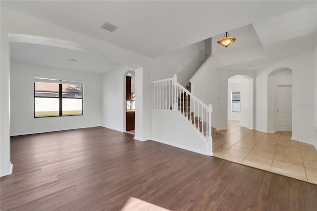7108 Harvest Glen Ln, Riverview, FL 33578 - unfurnished living room featuring arched walkways, wood finished floors, stairs, and baseboards
