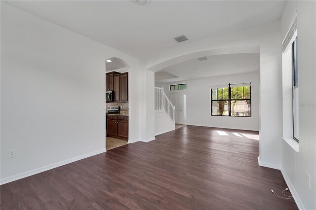 7108 Harvest Glen Ln, Riverview, FL 33578 - unfurnished living room featuring dark wood-style floors, stairway, baseboards, arched walkways, and recessed lighting