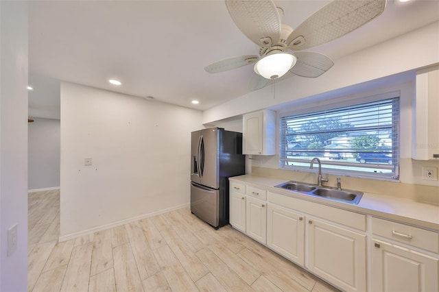 kitchen with light wood-style flooring, a sink, white cabinets, light countertops, and stainless steel fridge with ice dispenser